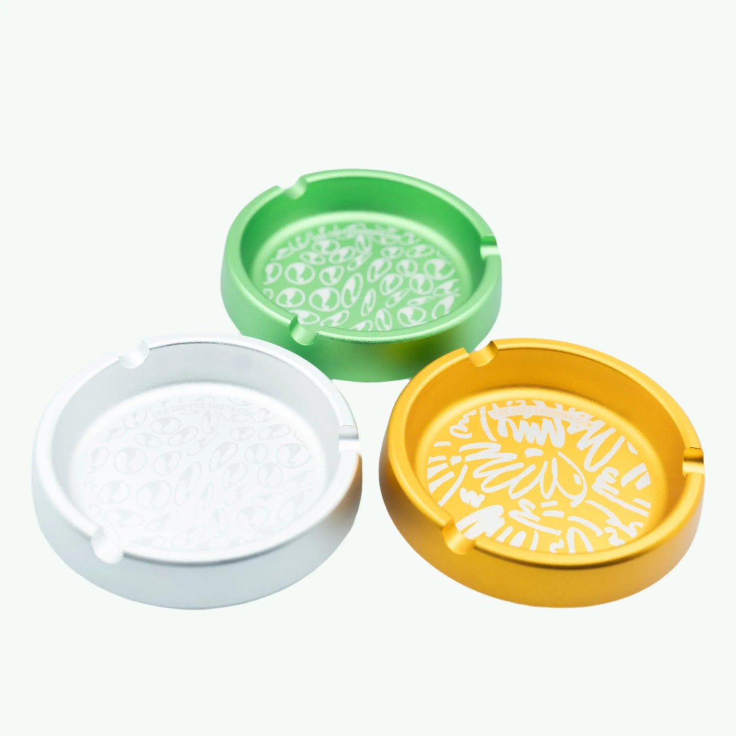 Metallic ashtray from The Coffeeshops with a shiny silver finish, round shape, and raised edges for cigarette ashes.