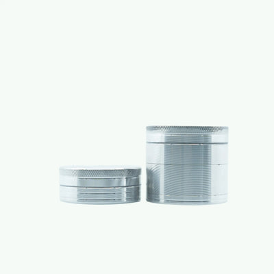 Large silver metal coffee grinder by The Coffeeshops with a sturdy cylindrical design and a clear top lid.